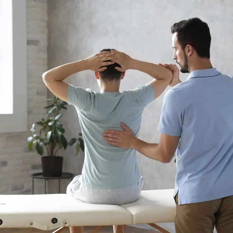 Clinical mentor guiding a physiotherapist's hand placement during a joint assessment