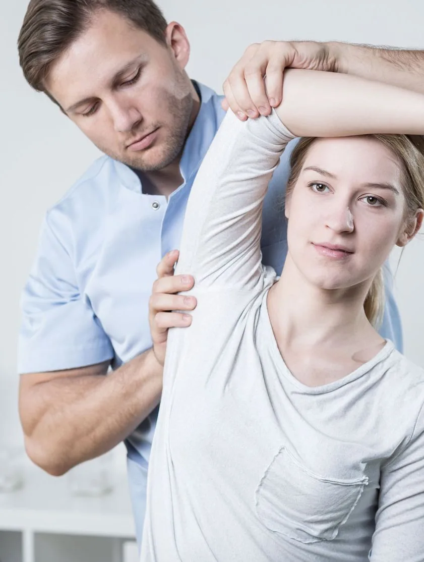 Physiotherapist testing a patient's hip range of motion on the treatment table